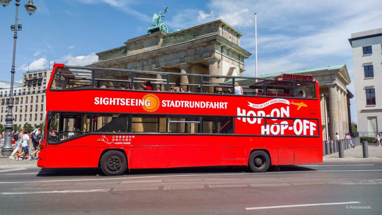 Menschen warten mit Ihren Tickets an den Sightseeing Bussen in Berlin. Diese Busse sind rot.